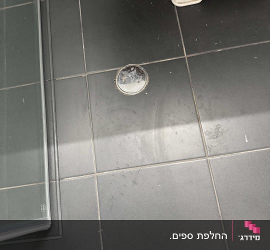 רצפת אריחים כהים בחדר רחצה עם פינה של מקלחון זכוכית